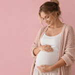 Mama werden schwangere Frau hält liebevoll ihren Babybauch vor rosa Hintergrund