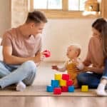 Fürsorgliche Eltern spielen mit ihrem kleinen Sohn zu Hause und zeigen was ist Co-Parenting in der Praxis