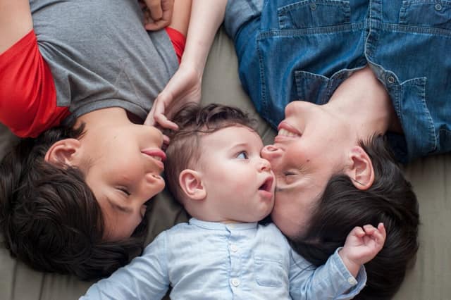 Gleichgeschlechtliche Eltern mit Kind spielend auf dem Boden zeigen liebevolle lesbische Familie im Alltag