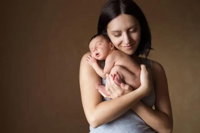 Alleine Baby bekommen junge Mutter hält liebevoll ihr neugeborenes Baby im Arm
