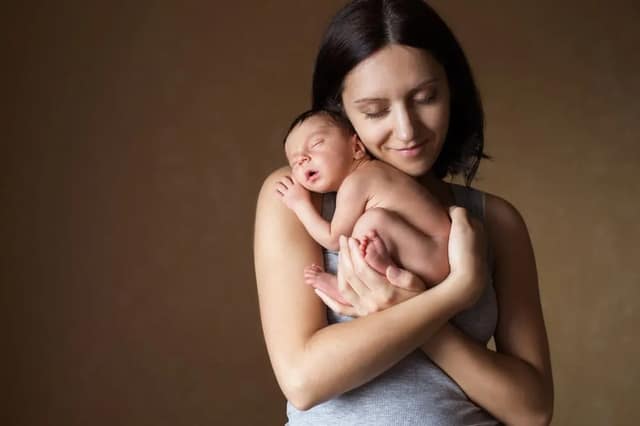 Alleine Baby bekommen junge Mutter hält liebevoll ihr neugeborenes Baby im Arm