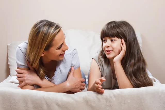 Mutter und Tochter liegen auf dem Bett und reden vertraulich um Kind Samenspende erklären in altersgerechter Weise