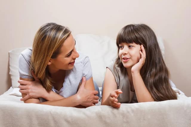 Mutter und Tochter liegen auf dem Bett und reden vertraulich um Kind Samenspende erklären in altersgerechter Weise