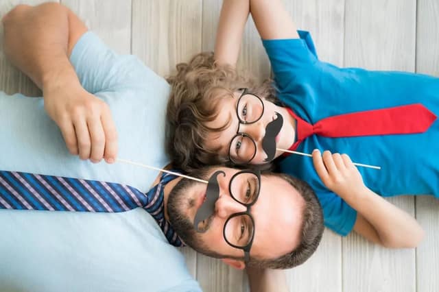 Vater und Kind mit lustigen Fake-Schnurrbärten und Brillen zeigen spielerischen Väterinstinkt und liebevolle Vater-Kind-Bindung