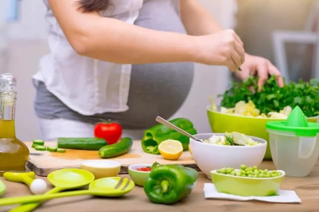 Ernährung Fruchtbarkeit schwangere Frau bereitet frisches Gemüse in der Küche zu