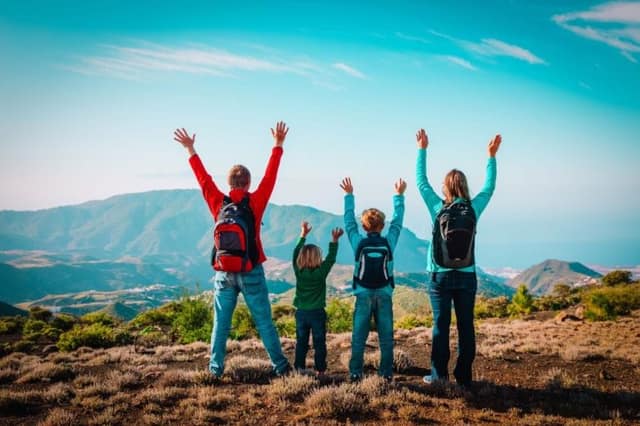 Glückliche Mama und Papa mit Kindern reisen in die Berge als Beispiel für platonische Elternschaft ohne romantische Beziehung