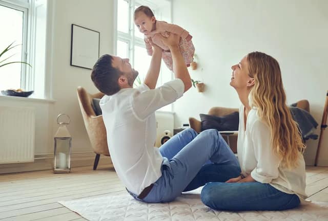 Tipps Co-Elternschaft glückliches Elternpaar spielt gemeinsam mit ihrem Baby im Wohnzimmer