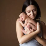 Alleine Baby bekommen junge Mutter hält liebevoll ihr neugeborenes Baby im Arm