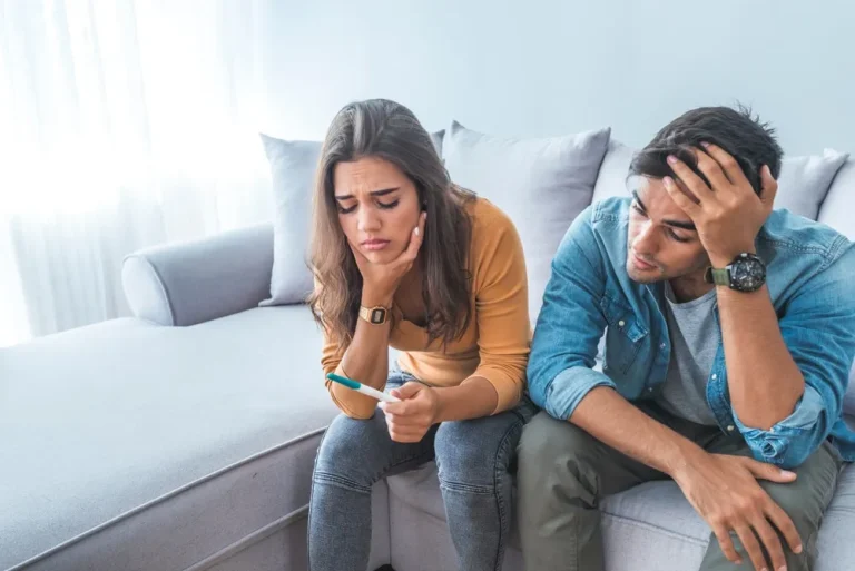 Stress Schwangerschaft Paar sitzt besorgt mit negativem Schwangerschaftstest auf dem Sofa