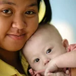 Baby Gammy mit seiner Mutter in einer emotionalen Nahaufnahme liebevoll im Arm gehalten