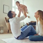 Tipps Co-Elternschaft glückliches Elternpaar spielt gemeinsam mit ihrem Baby im Wohnzimmer